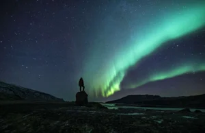 paesaggio notturno con uomo che ammira l'aurora boreale in Islanda