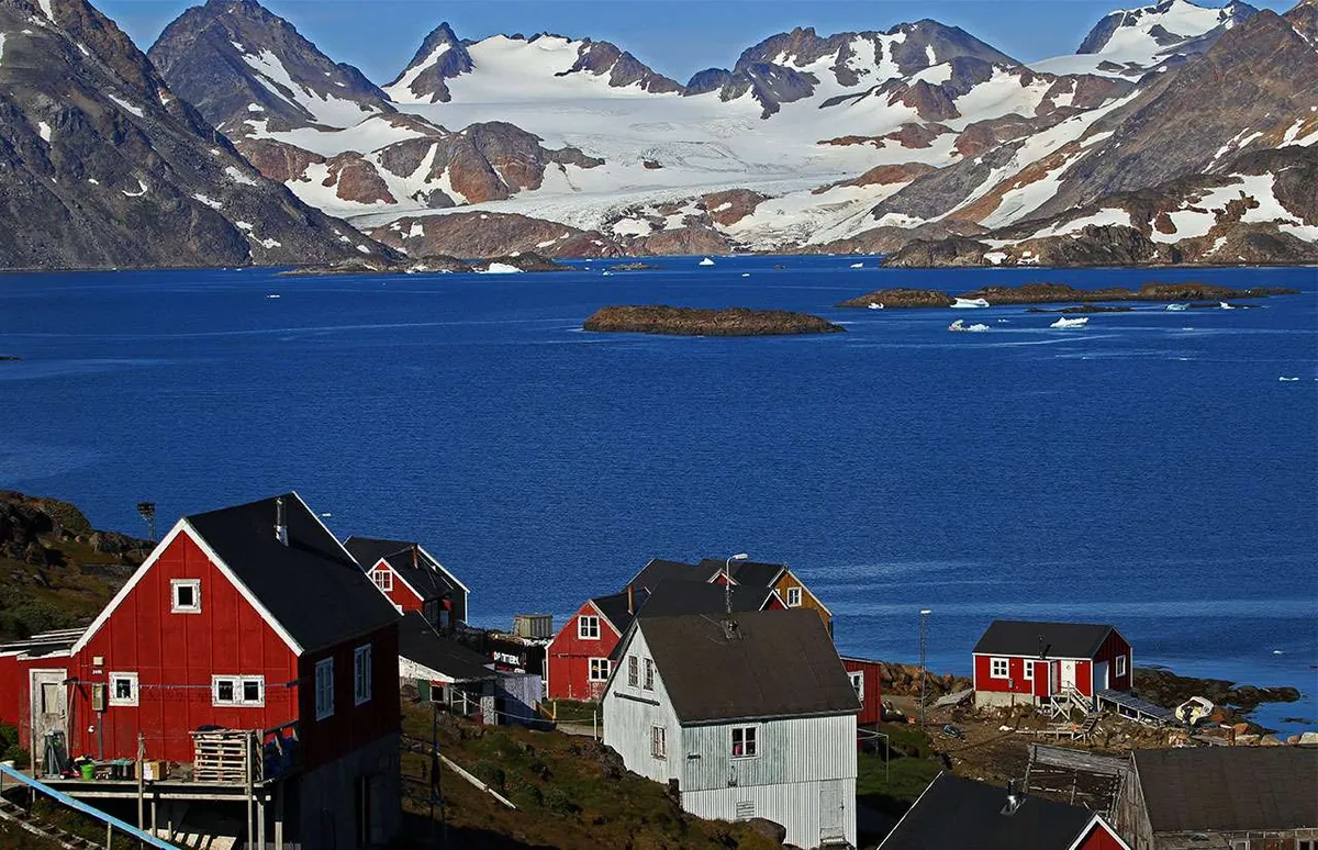 Groenlandia-Orientale-vista sul paese di kulusuk con le tipiche casetteolorate, il mare e le montagne innevate